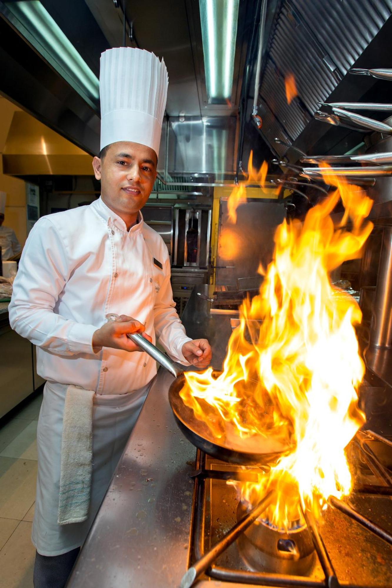 La Cigale Hotel Managed By Accor Доха Экстерьер фото A chef cooking with a flaming skillet